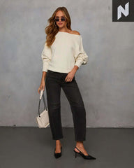 Stylish woman in off-shoulder Avena Knit Sweater paired with black jeans and heels, exuding a relaxed yet polished vibe.